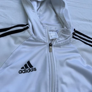 Adidas sport hoodie vit - Använd och väl omhändertagen Zip-tröja från Adidas Originals. Träningsjackan med de ikoniska kontrasterande 3-stripes på ärmarna. Butikpris: 899kr