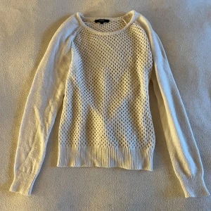 Vit stickad tröja - Säljer en vit stickad tröja med ett luftigt mönster. Tröjan har långa ärmar och ribbstickade muddar vid ärmslut och nederkant. Perfekt för att sticka ut lite extra!✨🤍