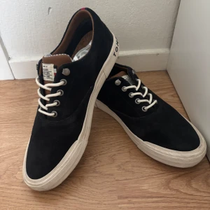 Mörkblå  sneakers från Tommy Hilfiger - Snygga mörkblå  sneakers från Tommy Hilfiger med vita snören och sula. Skorna har en korkinläggssula och en stilren design med märkets logga på hälen. Dom är mocha och är mörkblåa. Riktigt sköna och fina! Skriv gärna priset går att diskutera.