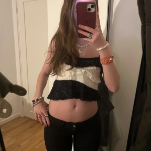 Svart och vit stickad tubtopp - Trendig stickad tubtopp i svart och vitt med volangdetaljer från Zara. Perfekt för en somrig look med sin croppade design. Toppen har en ribbad textur och smala axelband.