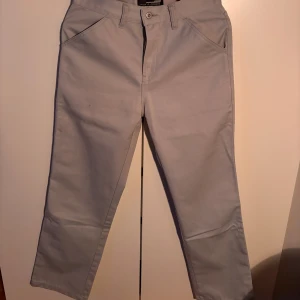Grå byxor från Jack & Jones - Snygga grå byxor från Jack & Jones med normal passform. Byxorna har praktiska fickor både fram och bak samt en diskret logga på baksidan. Perfekta för en stilren look. Ett äldre Jack & Jones par men i riktigt bra skick. Storlek 30/S. Knappt använda.