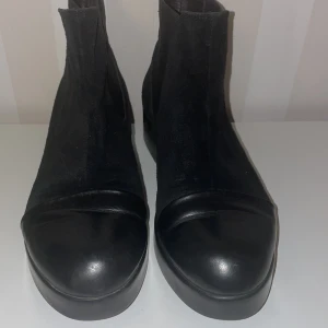 Svarta  boots i mocka och skinn - Snygga svarta chelsea boots med en kombination av mocka och skinn från Gulliver design.De har en klassisk design med elastiska paneler på sidorna för enkel på- och avtagning. Perfekta för både vardag och mer uppklädda tillfällen.