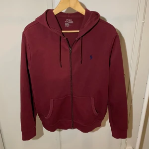 Vinröd Polo Ralph Lauren hoodie - Säljer en snygg vinröd hoodie från Polo Ralph Lauren. Storlek M. Skriv om ni har några frågor eller vill ha fler bilder!