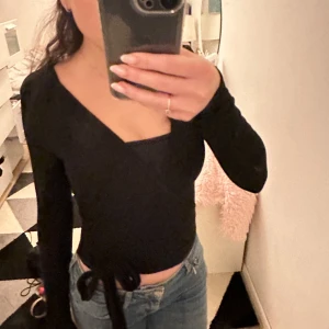 Svart omlottopp - Säljer en snygg svart långärmad topp med knytning. Perfekt för både vardag och fest! Använd endast en gång☺️