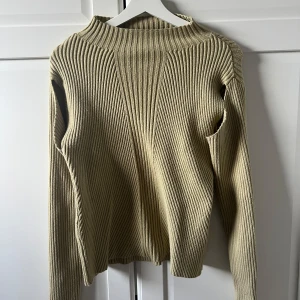 Grön ribbad tröja från NA-KD - Säljer en stilren grön ribbad tröja från NA-KD. Tröjan har en hög krage och långa ärmar, perfekt för kyligare dagar. Den är i storlek M och passar utmärkt till både jeans och kjol. Ett måste i garderoben för en trendig look! 