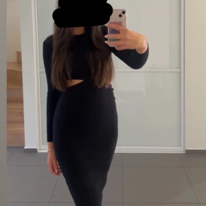 Svart ribbad klänning - Snygg svart ribbad klänning med långärmad design och en trendig cut-out detalj i midjan. Perfekt för alla tillfällen och årstider. 