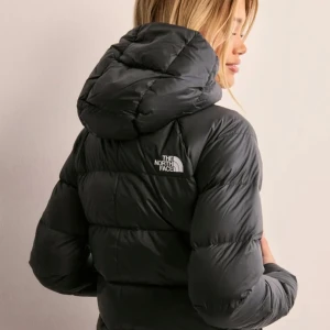 Svart dunjacka från The North Face - Snygg och varm svart dunjacka från The North Face med huva och dragkedja. Perfekt för kyliga dagar med sin pufferdesign som håller dig varm och bekväm. Den är som ny använt den endast en gång. Original pris 2899kr