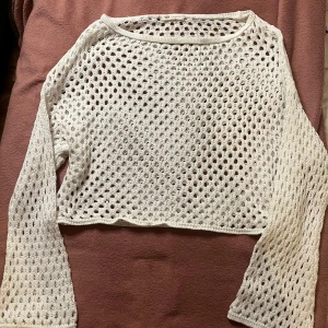 Vit stickad bolero från stradivarius - Säljer en vit stickad croppad tröja från STR. Tröjan har ett luftigt hålmönster och långa ärmar, perfekt för lager-på-lager-stil. Tillverkad i Turkiet.