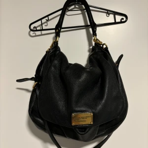 Svart axelväska från Marc by Marc Jacobs - Snygg svart axelväska i skinn från Marc by Marc Jacobs med guldfärgade detaljer. Vissa tecken på slitage men är i väldigt fint skick💕💕💕💕💕💕