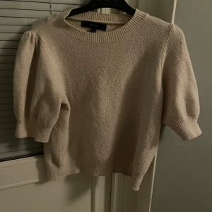 Beige tröja från Vero Moda - Säljer en stilren beige tröja från Vero Moda. Tröjan har puffiga trekvartsärmar och en rund halsringning. Perfekt för en chic och avslappnad look.