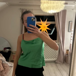 Grön linnetopp från Intimissimi - Säljer en snygg grön linnetopp från Intimissimi. Toppen har en elegant draperad halslinje och smala axelband. Perfekt för en stilren look.