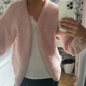 Rosa stickad kofta - Mysig rosa stickad kofta med långärmad design. Perfekt för kyliga dagar och ger en avslappnad look. Passar bra över en topp eller blus.