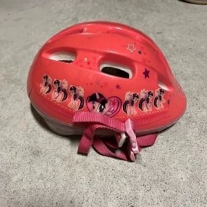 Rosa cykelhjälm med My Little Pony-motiv - Söt rosa cykelhjälm med My Little Pony-motiv och stjärnor. Justerbart rosa spänne för säker passform. Perfekt för små äventyrare som älskar ponnyer!