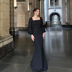 Svart långklänning med vida ärmar - Elegant svart långklänning med fyrkantig urringning och vida, långa ärmar. Klänningen har en figurnära passform som övergår i en lätt utsvängd kjol. Perfekt för formella tillfällen. Klänningen har aldrig används då den passade inte mig. Köpt 2500kr, säljs för 2000kr. Kommer med original dustbag och box. Storleken på klänningen är 42, men skulle säga att passformen är mer som 38. 