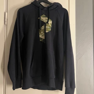 Hoodie  - Hoodie från Peak Performance i storlek M. Använd mycket och ena snöret är trasigt. Den är svart men ser lite mörkblå ut på bilderna.