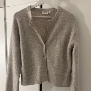 Beige kofta  - Mysig beige kofta med knappar framtill. Den har en enkel design med långa ärmar och ribbade kanter. Perfekt för kyliga dagar. Den är enbart använd några få gånger, ca 3 gånger.💕storlek M men sitter bra på mig som brukar ha xs/s