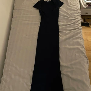 Mörkblå ribbad klänning - Snygg mörkblå ribbad klänning med korta ärmar och en smickrande slits bak. Perfekt för en stilren look.