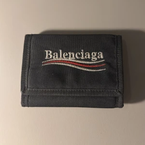 Svart plånbok från Balenciaga - En lite större plånbok från Balenciaga. Köpt från Balenciagas hemsida år 2019. Sköna detaljer på dragkedjan och embroidered logo. Pris kan diskuteras, vid fler frågor skicka PM!