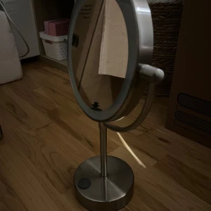 Sminkspegel med LED-belysning - Snygg och praktisk sminkspegel med inbyggd LED-belysning. Spegeln har en rund form och står på en stabil metallfot. Perfekt för att få till den perfekta sminkningen med bra ljus. Knappt använd 