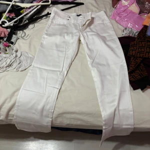 Vita byxor från Sukunya Boutique - Snygga vita byxor från Sukunya Boutique, tillverkade i Thailand. Byxorna har en klassisk design med knappar i midjan och raka ben. Perfekta för en stilren look.