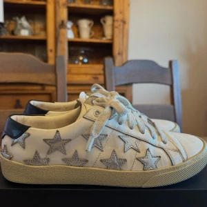 Vita sneakers med stjärnor från Saint Laurent - Säljer nu mina älskade YSL star sneakers då de inte kommer till användning längre. Köpta på vestaire för 2 år sedan. Går att få fram äkthetsbevis om det önskas. Storlek 37. 