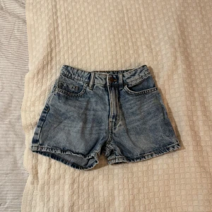 Blå jeansshorts från Lindex - Säljer ett par klassiska blå jeansshorts från Lindex. De är högmidjade med knapp och dragkedja framtill. Den har storlek 134 och jag söljer den eftersom den är alldeles för liten för mig 💕🌸🌟