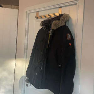 Parajumper Kodiak - Säljer en svart jacka från Parajumpers med pälsdetaljer på huvan. Jackan har flera fickor och en dragkedja framtill. *Jackan saknar en knapp överst* annars perfekt för kalla dagar.