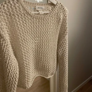 Beige stickad tröja från Monki - Säljer en beige stickad tröja från Monki i storlek S. Tröjan har ett luftigt stickat mönster och långa ärmar. Perfekt för lager-på-lager-stil eller som en lätt överdragströja.