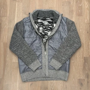 Grå cardigan - Tja, säljer en helt sprillans ny grå stickad cardigan med en grå, svart aktig ”päls” inuti som håller dig varm under de kyliga dagarna. På framsidan så är det lite jack material medans på baksidan så är det helt stickat. Storlek XS. (Helt ny)