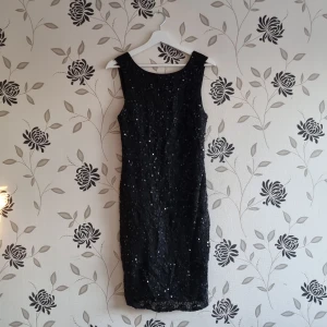 Svart glittrig klänning från Fracomina, Strl: S/36, nyår - Snygg svart klänning från Fracomina med glittrande detaljer. Den är ärmlös och har en figurnära passform som framhäver silhuetten. Perfekt för en kväll ute eller en speciell tillställning.