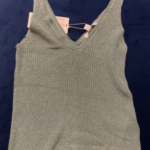 Grön stickad linnetopp från Amisu - Snygg grön stickad linnetopp från Amisu med v-ringning. Perfekt för lager-på-lager eller som den är. Mjuk och bekväm med en stilren design.