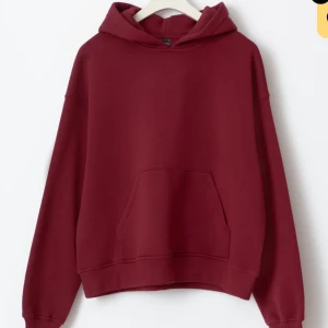 Vinröd hoodie - Säljer en stilren vinröd hoodie ifrån Gina tricot med en klassisk design. Den har en rymlig magficka och en bekväm huva. Perfekt för en avslappnad look. Oanvänd.