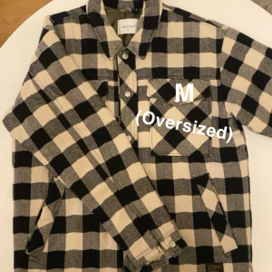 Svart vindjacka med dragkedja - Snygg svart vindjacka med dragkedja och huva. Perfekt för blåsiga dagar och enkel att matcha med olika outfits. Jackan har en praktisk design med justerbara snören i huvan. Båda kostar 100kr/st!