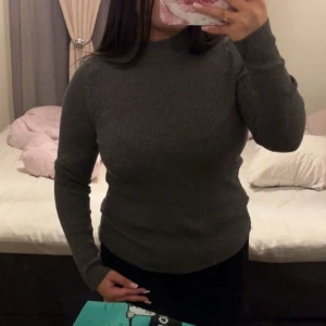 Grå ribbad tröja - Säljer en stilren grå ribbad tröja med lång ärm och hög krage. S/M