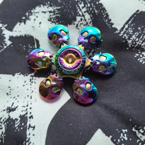 Fidget spinner med dödskallar och vingar - Cool fidget spinner i regnbågsfärger med unikt designade dödskallar och vingar. Perfekt för att hålla händerna sysselsatta och för att imponera på vänner med dess iögonfallande utseende. Säljer båda, köparen köper bägge.