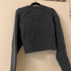 Blå stickad tröja - Mysig blå stickad tröja med långa ärmar och ribbstickade detaljer vid ärmslut och nederkant. Perfekt för kyliga dagar.