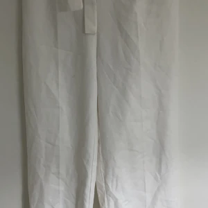 Vita byxor med knytband - Säljer ett par vita byxor med knytband i midjan. Byxorna har en loose passform och är perfekta för en avslappnad stil. De är tillverkade i ett lätt material som passar bra för varmare väder. Jag köpte dem på någon lokal butik i Turkiet. 