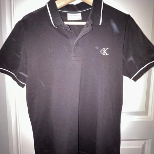 Svart pikétröja Calvin Klein - Snygg svart pikétröja från Calvin Klein. Den är nästan helt oanvänd så den är i nyskick. Hör av er vid minsta lilla fundering!