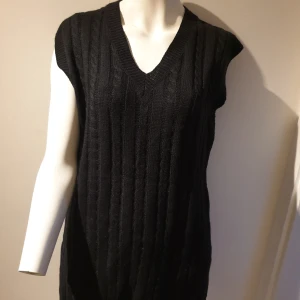  Stickad väst - Snygg svart stickad väst med v-ringning. Perfekt för lager-på-lager-stil och ger en klassisk touch till din outfit. Den ribbade strukturen ger en extra dimension och stil.