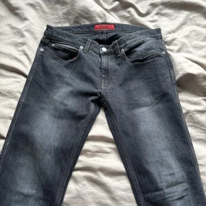 Grå jeans från Hugo - Snygga grå jeans från Hugo med en unik färgbehandling. De har en klassisk femficksdesign och en diskret tvättad look. Insidan av fickorna är röda vilket ger en cool kontrast. Perfekta för en stilren vardagslook. (Pris kan diskuteras 