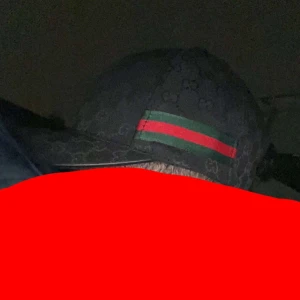 Svart keps med gröna och röda detaljer - Snygg svart keps med diskret mönster och ikoniska gröna och röda ränder på sidan. Perfekt för en stilren look.