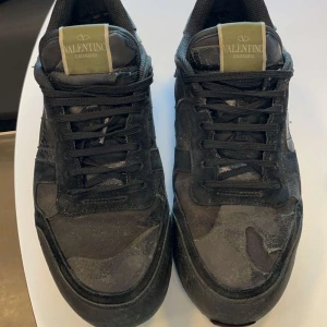 Valentino Garavani sneakers i camouflage - Snygga Valentino Garavani sneakers i en cool camouflage-design. Skorna har en klassisk snörning och är tillverkade i en kombination av material som ger en unik look. Perfekta för dig som vill ha en stilren men ändå iögonfallande stil.