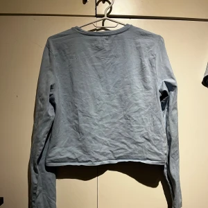 Ljusblå croppad tröja från BikBok - Säljer en ljusblå croppad tröja från BikBok. Tröjan har långa ärmar och en rund halsringning. Perfekt för en avslappnad stil. Passar bra till jeans eller kjol för en trendig look.