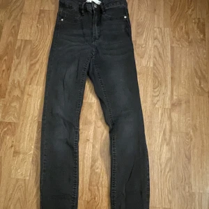 Svarta jeansbyxor - Snygga svarta jeansbyxor med hög midja och klassisk femficksdesign. Perfekta för en stilren look. De har en dragkedja och knapp framtill.