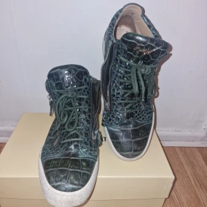 Gröna sneakers från Giuseppe Zanotti - Snygga gröna sneakers med krokodilmönster och dragkedja på sidan från italienska märket Giuseppe Zanotti. Perfekta för att ge din outfit en unik touch. Kostade över 3000 kr, det kan behövas nya innesulor därav lågt pris. Garderobsrensning så kika gärna på övriga auktioner. 
