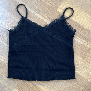 Svart ribbat spets linne från Gina Tricot - Säljer en svart ribbat spets linne från Gina Tricot. Sitter tajt och har en fin passform. 