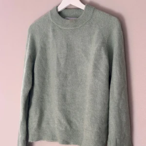 Grön stickad tröja från Zara - Mysig grön stickad tröja från Zara. Perfekt för kyliga dagar med sin mjuka och varma känsla. Tröjan har långa ärmar och en rund halsringning. Materialet består av en blandning av nylon, ull, alpacka och akryl. Passar perfekt till våren och påsk. 