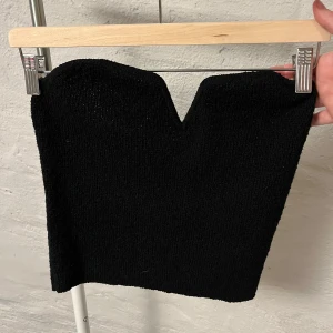 Tubtopp - Snygg svart tubtopp med en hjärtformad urringning. Perfekt för en stilren och elegant look. Toppen är enkel att matcha med olika outfits och passar bra till både jeans och kjol. Den har en metal skena vid v ringningen men inget som känns.