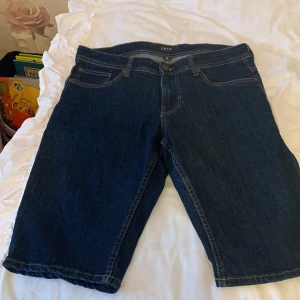 Mörkblå jeansshorts - Snygga mörkblå jeansshorts från SMIBO. Klassisk design med fem fickor och knappgylf. Perfekta för en avslappnad stil.