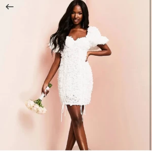 Vit kort klänning med puffärmar - Säljer en superfin vit kort klänning med puffiga ärmar och en unik textur. Klänningen har en söt och romantisk stil med en figurnära passform. Perfekt för speciella tillfällen! 💐 helt oanvänd sitter prislapp kavar perfekt för studenten!❤️kostar över 1000kr ny